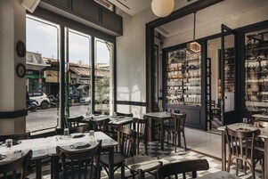 A restaurant with tables and chairs, large windows, and a view of the street.