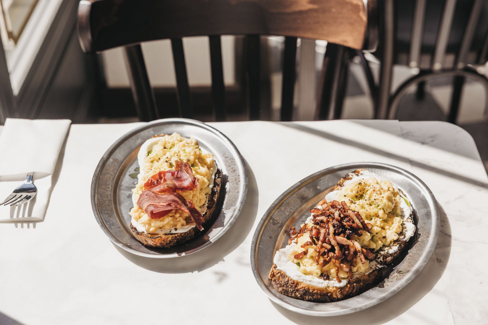 Dos platos de comida sobre una mesa con un tenedor a la izquierda.