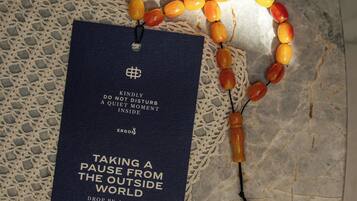 Un collar de cuentas de oración y una tarjeta con un mensaje sobre una superficie rugosa.