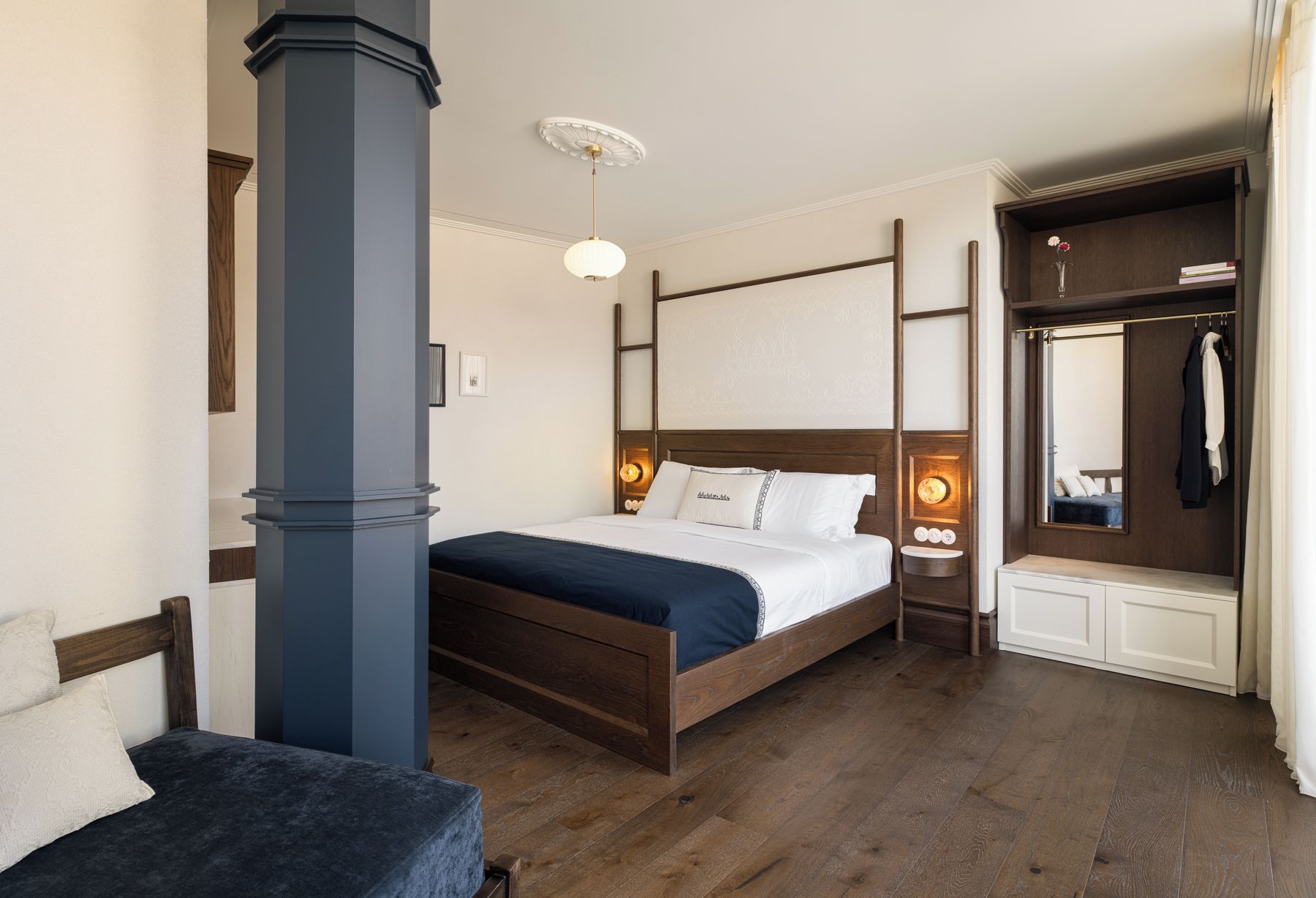 Et hotelværelse med en træseng, et natbord med en lampe, et garderobeskab og et spejl.