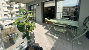 A balcony with a table and chairs, a potted plant, and a view of the cityscape. - Spacious and elegant T4, city center (Vannes)