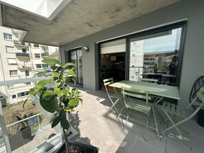 Ein Balkon mit Tisch und Stühlen, einem Blumentopf und Blick auf die Stadt.