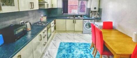 A compact kitchen with a dining area, a washing machine, and a window with a view.