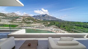 En terrass med utsikt över ett bergigt landskap, en pool och en matplats.