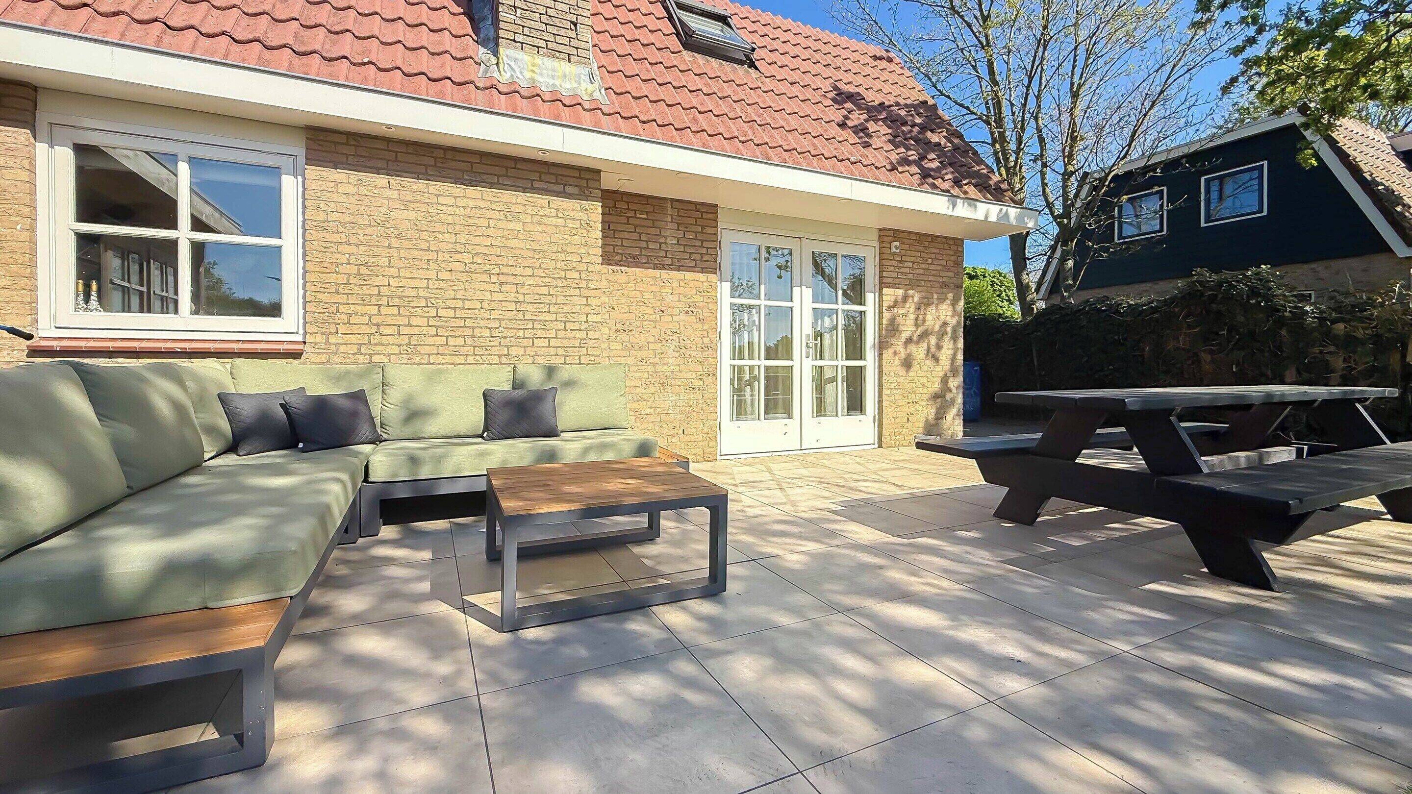 A patio area with a sofa, a table, and a picnic table.