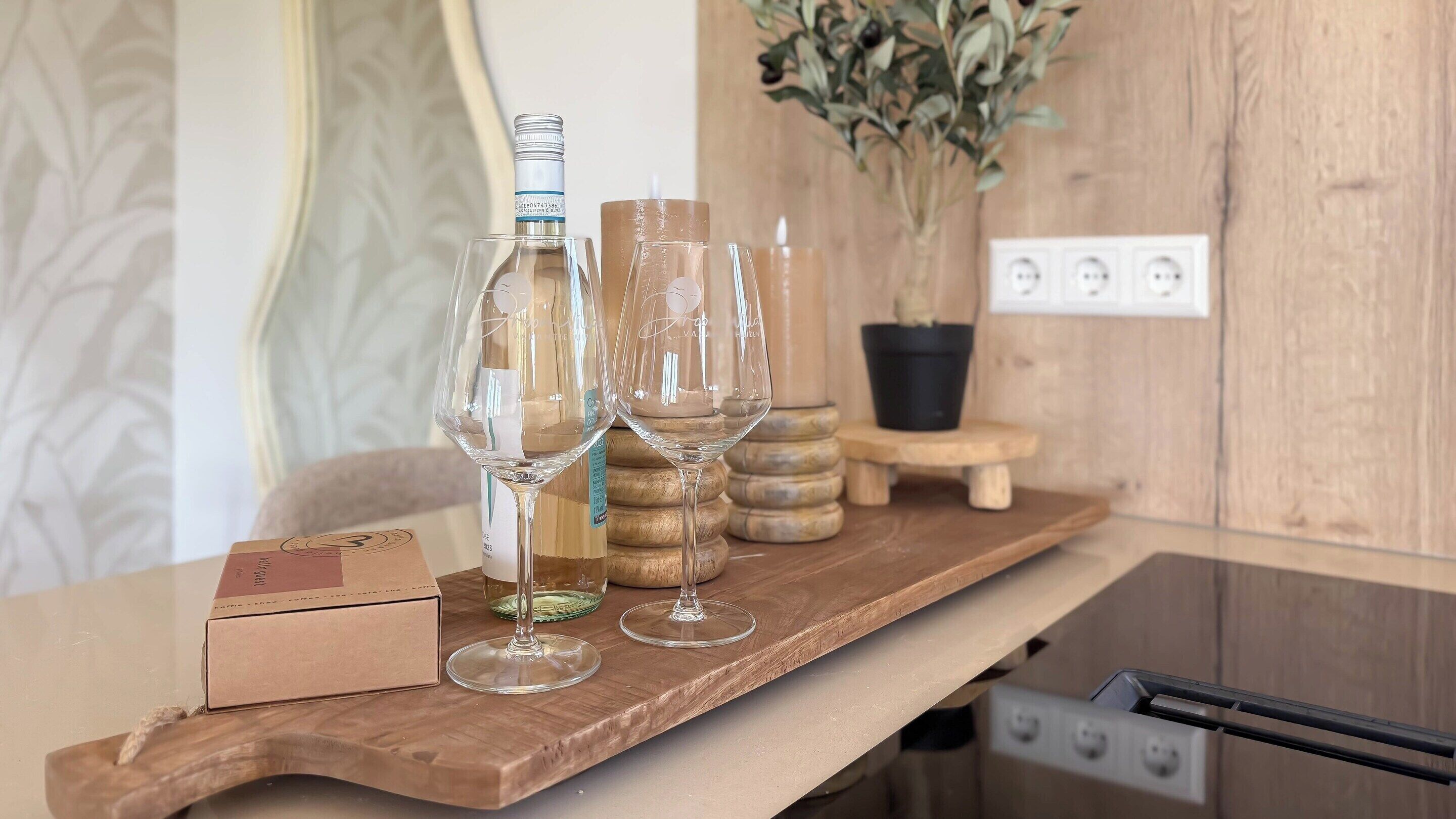 A wooden shelf with wine bottles and glasses, a potted plant, and a power outlet.