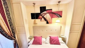 A hotel room with a bed, two bedside lamps, a headboard, and a wall with three artworks. - Double with Terrace (Roma)