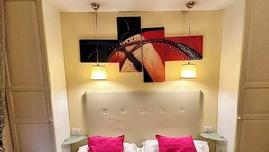 A hotel room with a bed, two nightstands, a headboard, and wall art. - Double with Terrace (Roma)