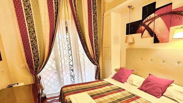 A hotel room with a bed, curtains, a headboard, and a painting on the wall. - Double with Terrace (Roma)