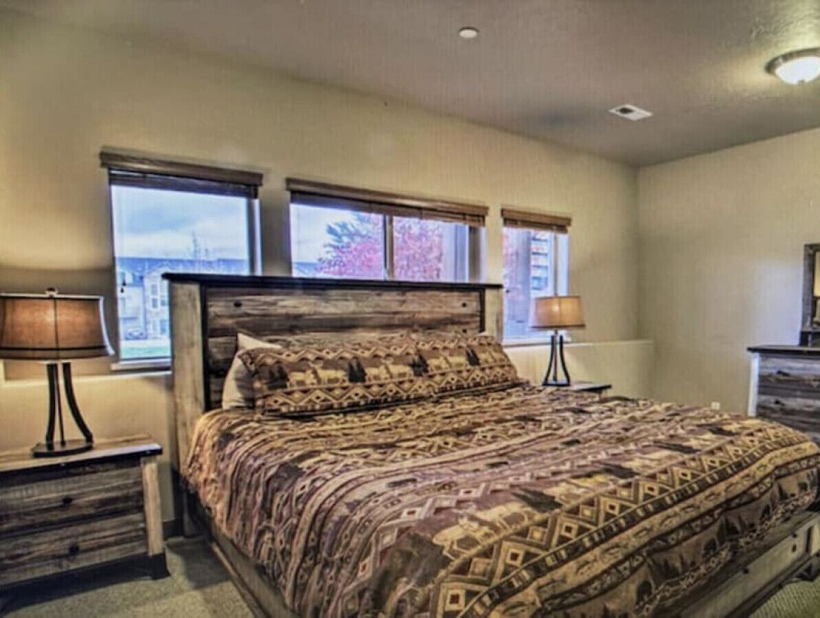A bedroom with a large bed, two bedside tables, and a window with a view.