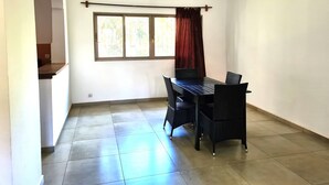 Une pièce comprenant une table et des chaises, une fenêtre avec des rideaux et un luminaire suspendu.