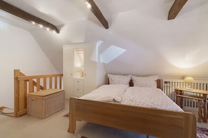 A bedroom with a wooden bed, a white wardrobe, a wooden chest of drawers, and a small table with a lamp. - Apartment “Berlin” with Shared Terrace, Garden and Wi-Fi (Pellworm)