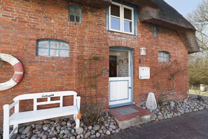 A brick building with a white bench, a door, and a window. - Apartment “Berlin” with Shared Terrace, Garden and Wi-Fi (Pellworm)
