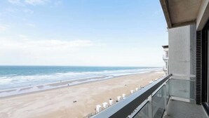 Blick auf einen Strand von einem Balkon aus, mit blauem Himmel.