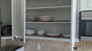 Eine Küche mit weißen Schränken, einer gefliesten Spritzschutzwand und einer eingebauten Mikrowelle.