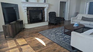 Ein Wohnzimmer mit Kamin, Fernseher, Sofa und Couchtisch.