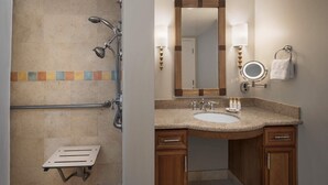 Ein Badezimmer mit Dusche, Waschbecken, Spiegel und Handtuchhalter.