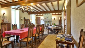 Comedor con sillas de madera, una mesa con mantel rojo y una lámpara de araña.