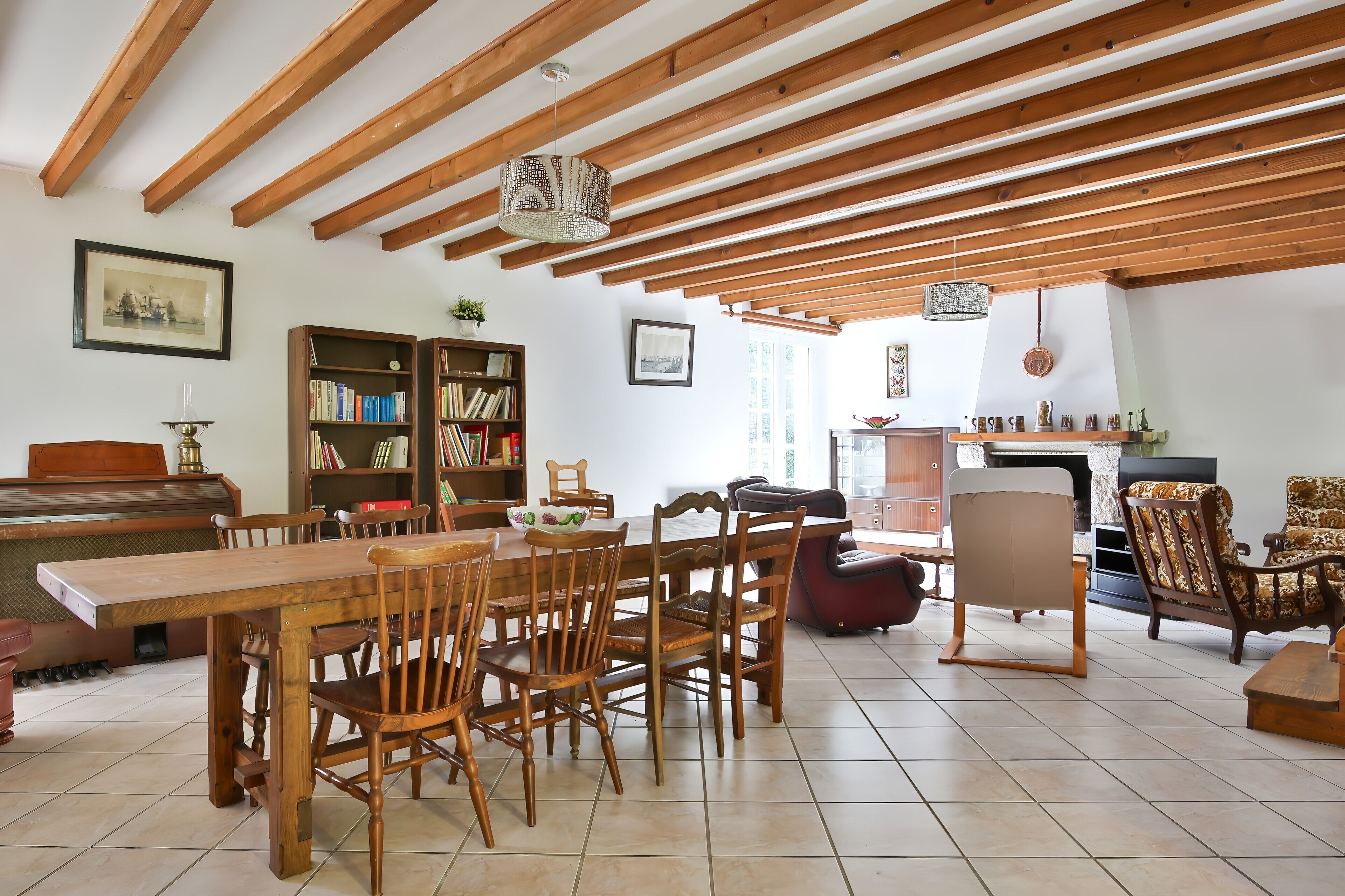 Un coin repas avec des chaises et une table en bois, une bibliothèque et un piano.