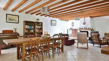 Un coin repas avec des chaises et une table en bois, une bibliothèque et un piano.