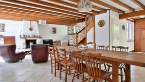 Un salon spacieux avec une table à manger en bois, des fauteuils en cuir et une cheminée.