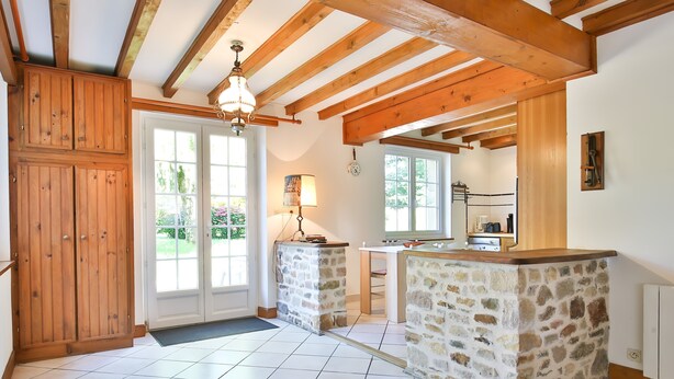 Une cuisine dotée de plans de travail en pierre, de poutres en bois et offrant une vue sur l’extérieur.