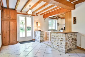 Une cuisine dotée de plans de travail en pierre, de poutres en bois et offrant une vue sur l’extérieur.