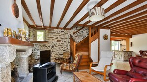 Un salon chaleureux avec un mur en pierre, un escalier en bois et une cheminée.