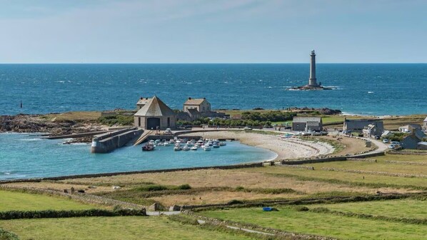 Un pueblo costero con un faro, puerto y edificios.