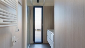 A narrow hallway with a radiator, a power outlet, and a door leading to a room with a window. - Stylish Boathouse on Lake Sneeker (Offingawier)