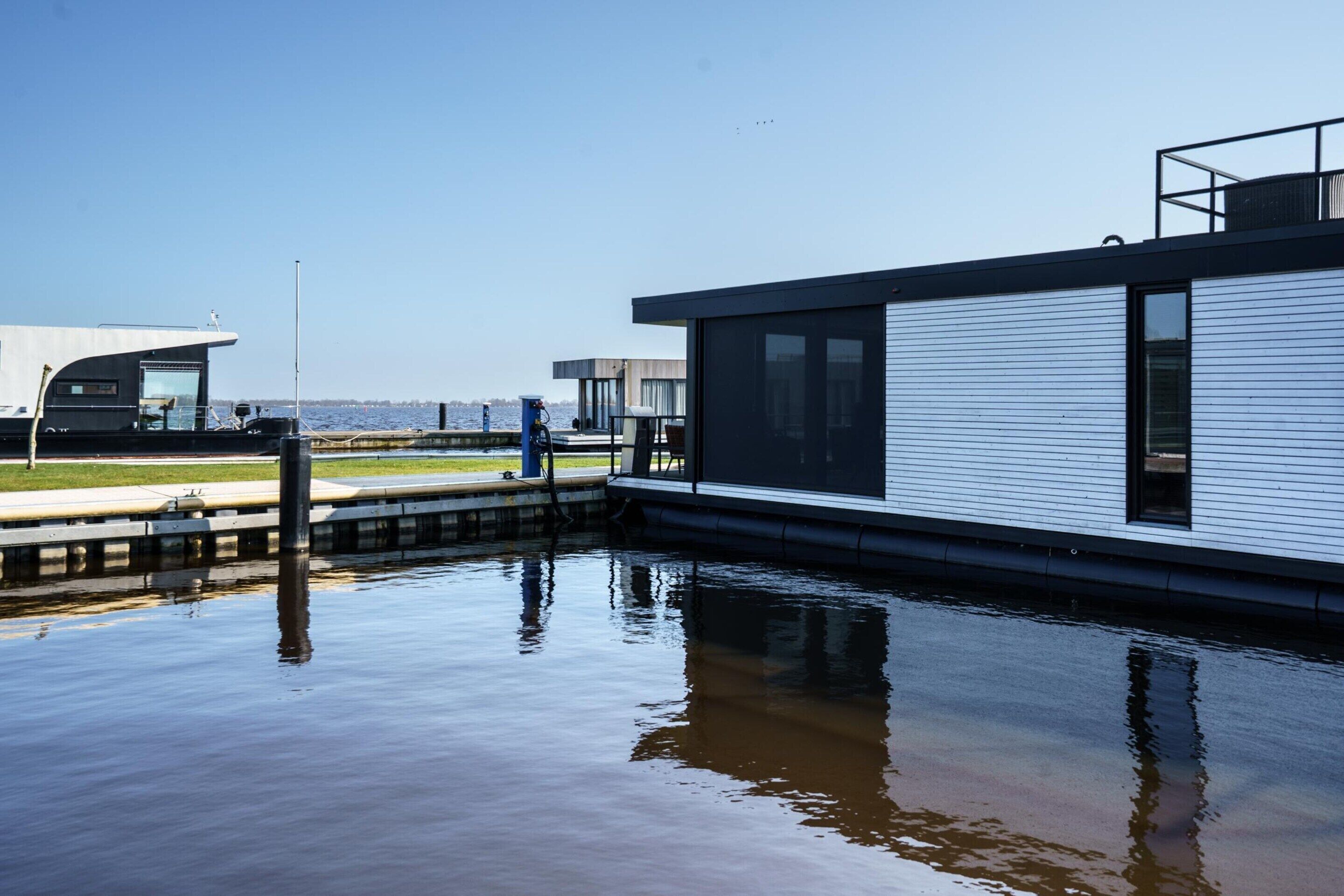 A modern building with large windows, a dock, and a calm water body.