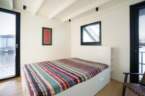 A bedroom with a bed, a chair, a window, and a door. - Stylish Boathouse on Lake Sneeker (Offingawier)