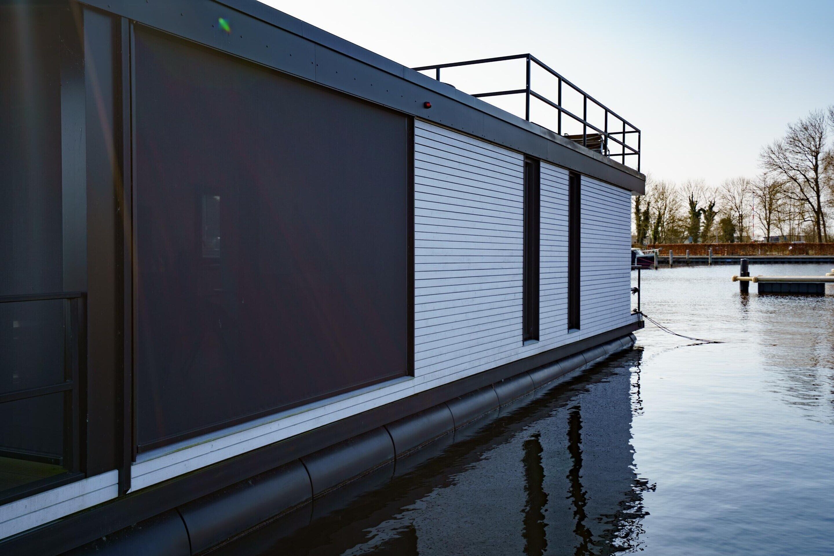 Un edificio moderno con amplios ventanales, techo plano y un cuerpo de agua en primer plano.