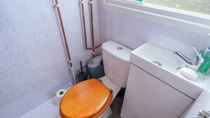 A bathroom with a toilet, sink, and a fire exit sign.