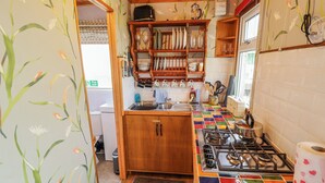 A compact kitchen with wooden cabinets, a gas stove, and a colorful tile backsplash.