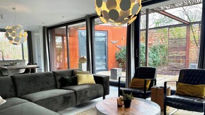 Uma sala de estar moderna com um sofá em formato de L, uma mesa de centro redonda e uma área de jantar com mesa e cadeiras.