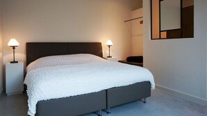 Um quarto moderno com uma cama, duas luminárias de cabeceira, uma mesa de cabeceira e um espelho grande na parede.