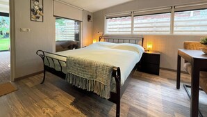 A bedroom with a bed, bedside tables, a desk, a chair, a window, and a door. - Quiet Wellness Villa in Bellingwolde (Bellingwolde)