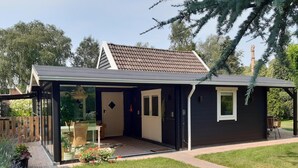 A modern house with a glass door entrance, a small patio, and a well-maintained lawn. - Quiet Wellness Villa in Bellingwolde (Bellingwolde)