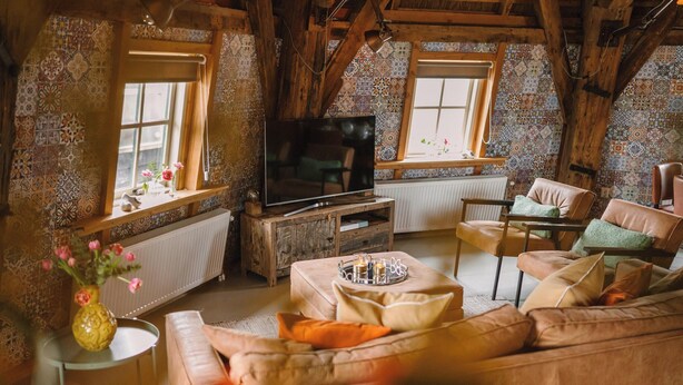 Una sala de estar acogedora con televisión, asientos cómodos y un jarrón decorativo.
