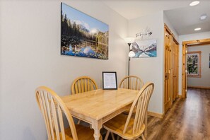 A dining area with a wooden table and chairs, framed artwork on the walls, and a sign on the table. - Fall River Hideout • Private Hot Tub • Near RMNP (Estes Park)