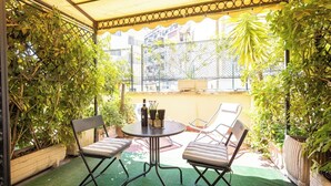 A covered patio with a table and chairs, surrounded by potted plants and a view of buildings. - Superior Double with Terrace (Roma)
