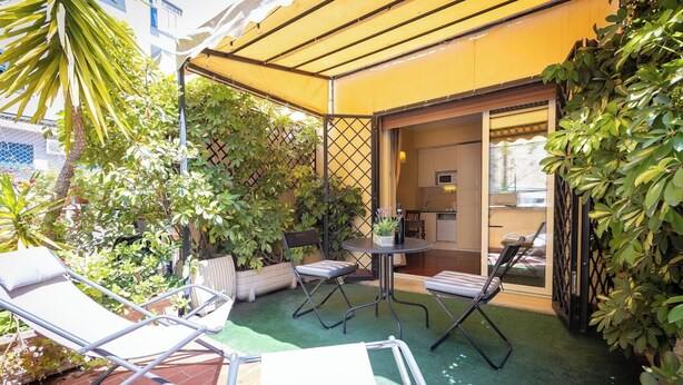 A patio with a table and chairs, surrounded by potted plants and a yellow awning. - Superior Double with Terrace (Roma)