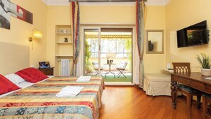 A hotel room with a bed, a desk, a television, a small table with chairs, and a sliding glass door to an outdoor area. - Superior Double with Terrace (Roma)