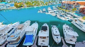Un port de plaisance où sont amarrés de nombreux bateaux, entouré de bâtiments et de verdure.