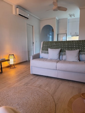 A living room with a sofa, a lamp, a ceiling fan, and a kitchen in the background. - Sunshine haven at  Casa Palma Verde, La Marquesa Golf course, near Rojales, Spa (VC)