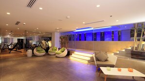 A modern interior with a seating area, exercise equipment, and a staircase with illuminated steps. - Best Plus Aurora Hotel (Riyadh)