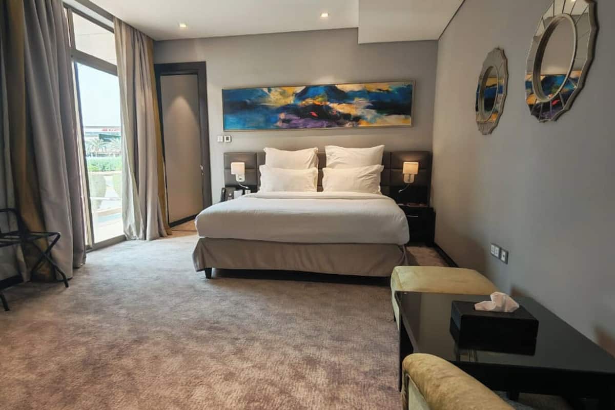 Habitación de hotel con una cama grande, un escritorio, una silla y un cuadro en la pared.