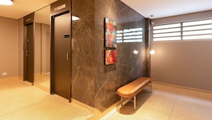 A modern lobby with a marble wall, a bench, and a door. - ZEST Cardeal (São Paulo)