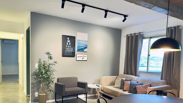 A modern living room with a sofa, armchair, dining table, and a potted plant. - ZEST Cardeal (São Paulo)